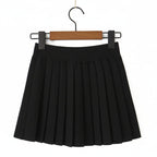 A black pleated mini skirt hanging from a wooden hanger with black clips against a plain white background.